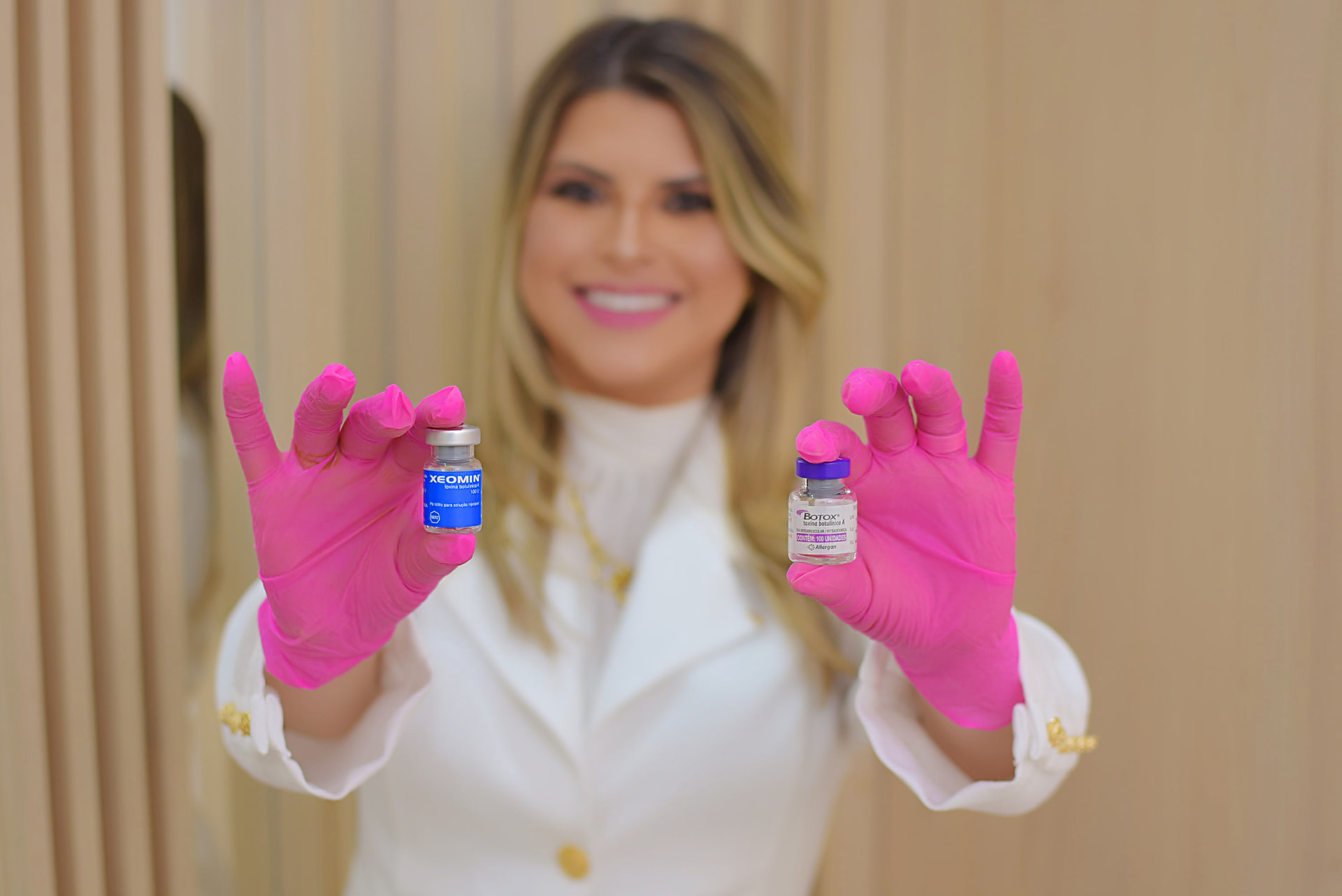 Dra. Flávia Seródio segurando frascos de toxina botulínica com luvas cor de rosa